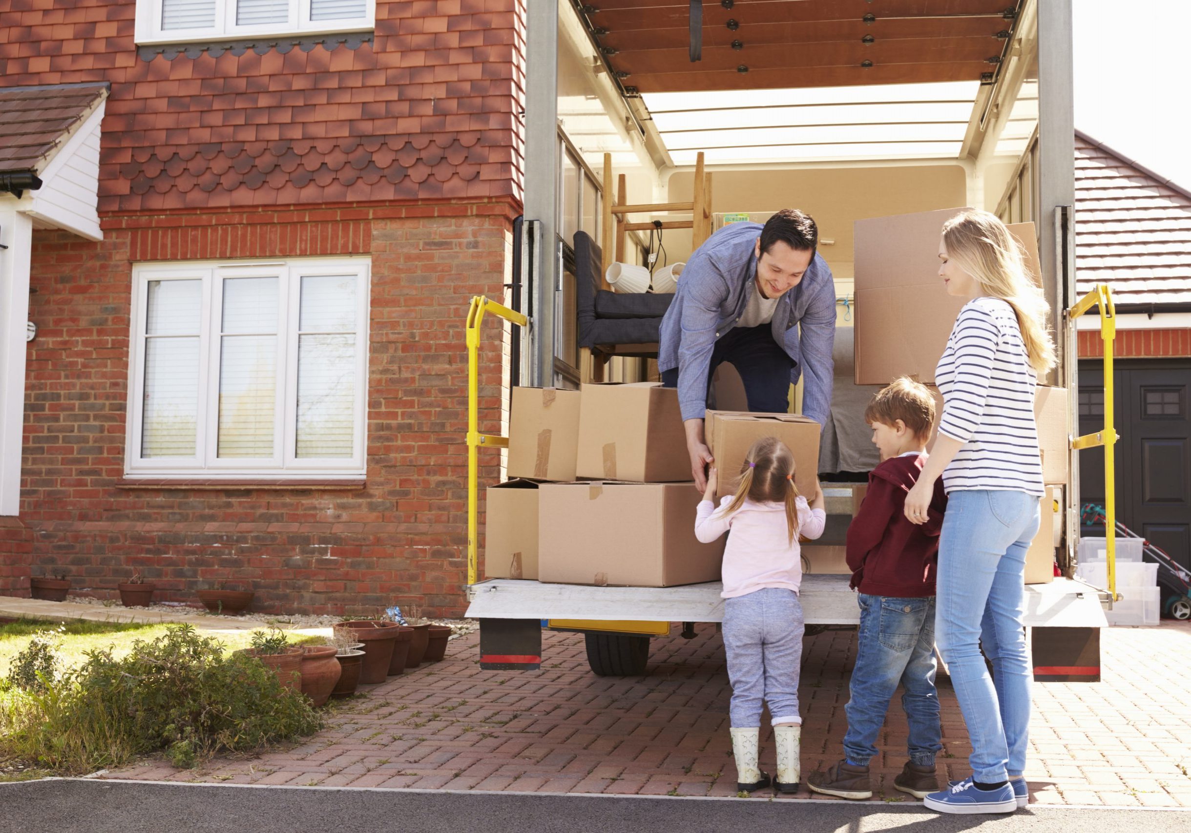 Family Unpacking Moving In Boxes From Removal Truck